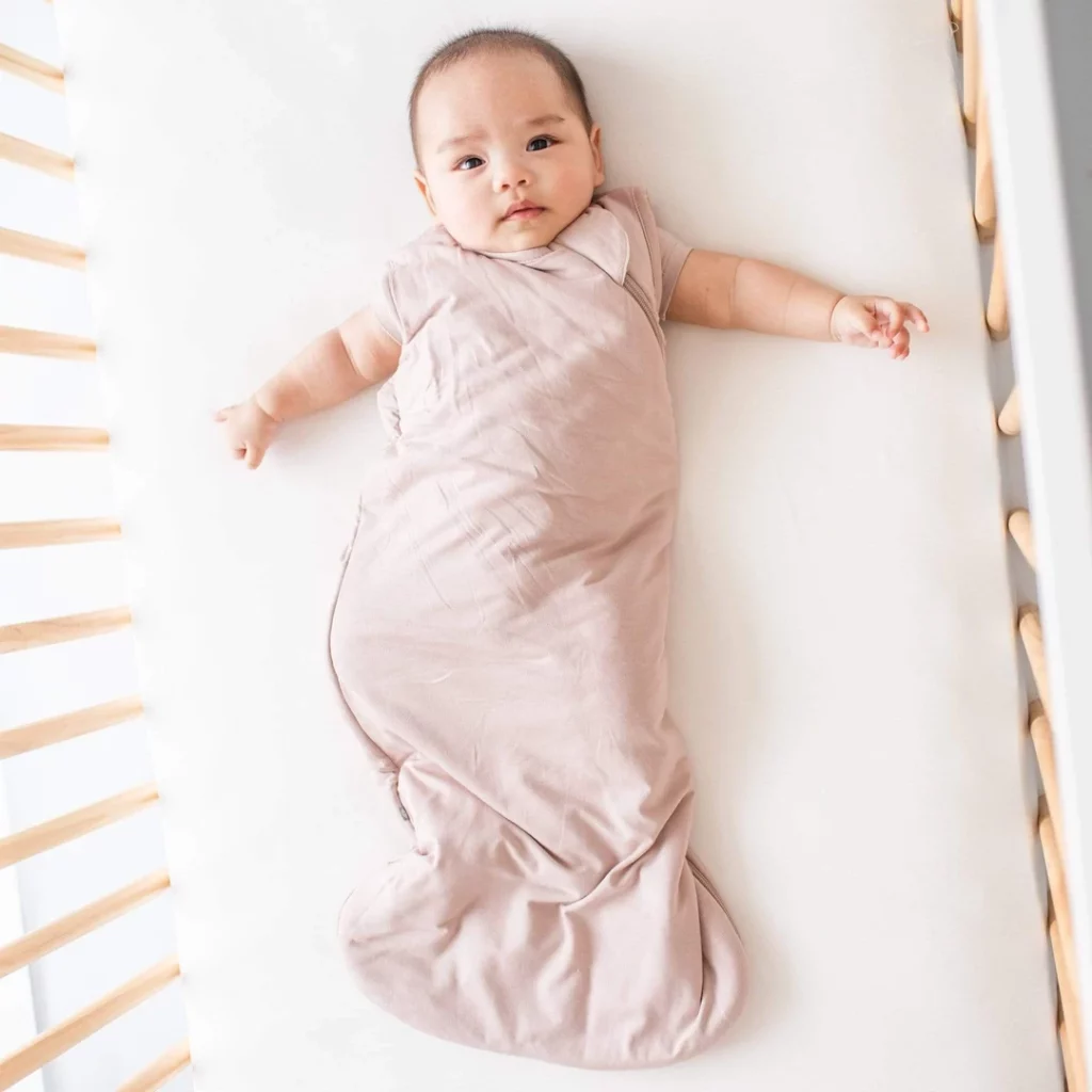 baby in crib in a pink sleepsack