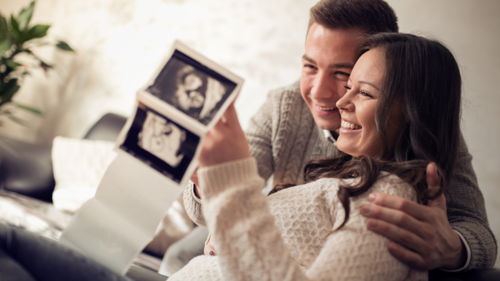 couple smiling looking at ultrasound pictures